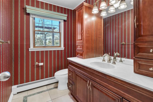 Half bathroom featuring a notable chandelier, toilet, tile patterned flooring, wallpapered walls, and a baseboard heating unit | Image 12