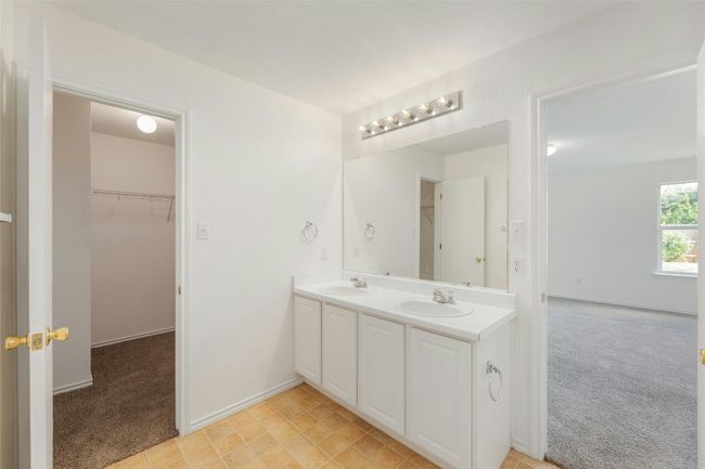 Bathroom featuring double vanity, a walk in closet, baseboards, and a sink | Image 8