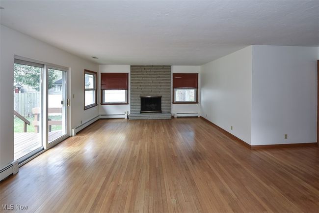 Unfurnished living room featuring a baseboard heating unit, light wood-style flooring, a baseboard radiator, and a wealth of natural light | Image 20