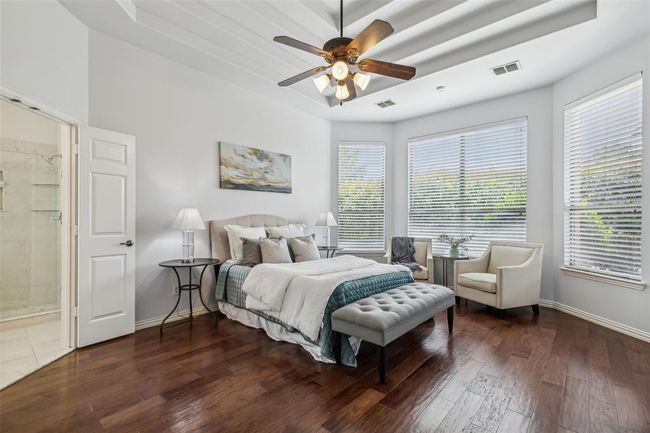 Bedroom with ensuite bath, dark hardwood / wood-style floors, ceiling fan, and multiple windows | Image 14