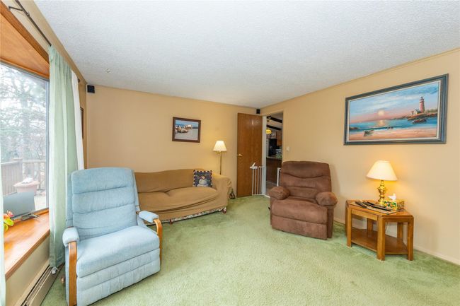 Living room with carpet floors, a baseboard heating unit, and a textured ceiling | Image 13