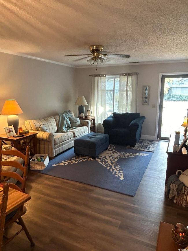 Living area featuring plenty of natural light, a textured ceiling, wood finished floors, ceiling fan, and crown molding | Image 11
