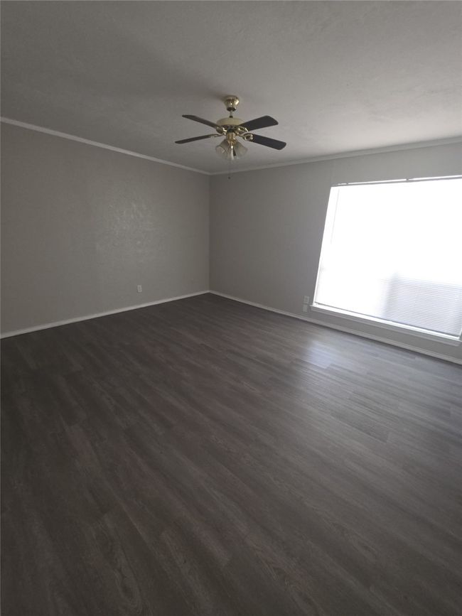 Spare room featuring dark wood finished floors, ornamental molding, and ceiling fan | Image 6