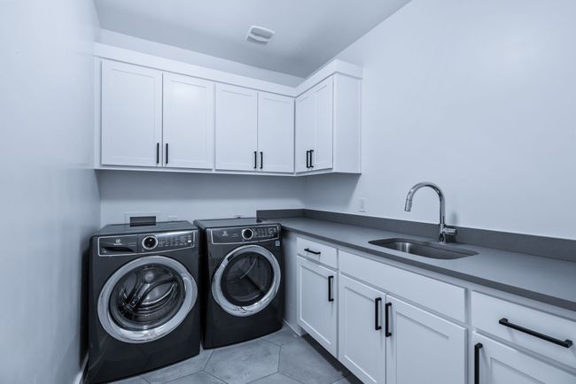 Washroom featuring cabinet space, washing machine and dryer, and light tile patterned flooring | Image 30