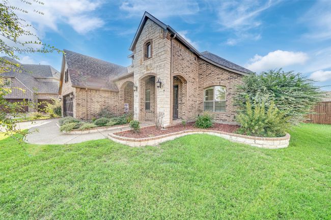 French country home with a front yard, brick siding, roof with shingles, and a garage | Image 40