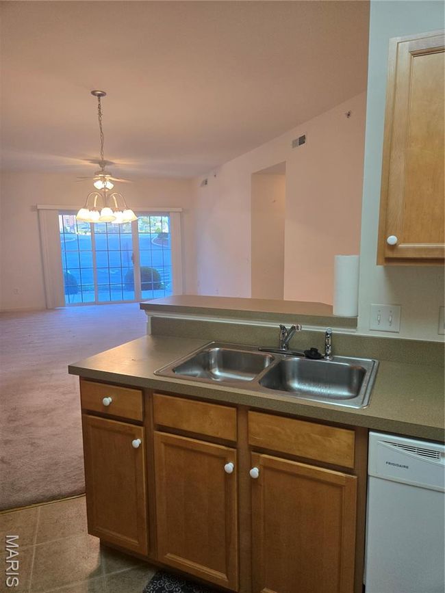 Kitchen with dishwasher, brown cabinetry, a chandelier, carpet, and a peninsula | Image 10