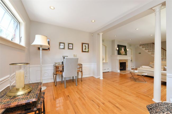 Office featuring a wainscoted wall, light wood-style floors, a fireplace, and a baseboard heating unit | Image 8