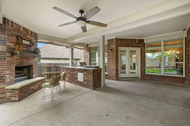 View of patio with an outdoor brick fireplace, exterior kitchen, and ceiling fan | Image 29