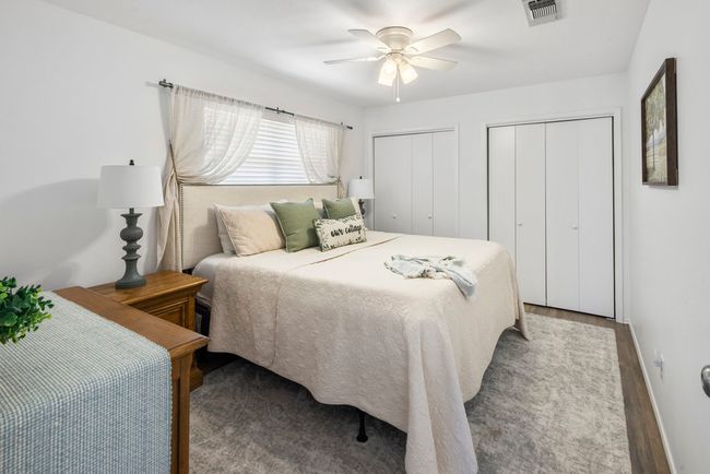 Bedroom with visible vents, two closets, baseboards, ceiling fan, and wood finished floors | Image 13
