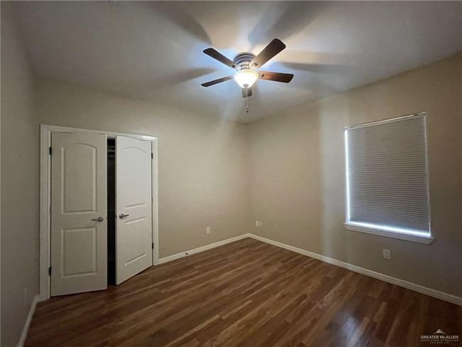 Unfurnished bedroom with dark wood finished floors, a closet, and ceiling fan | Image 11