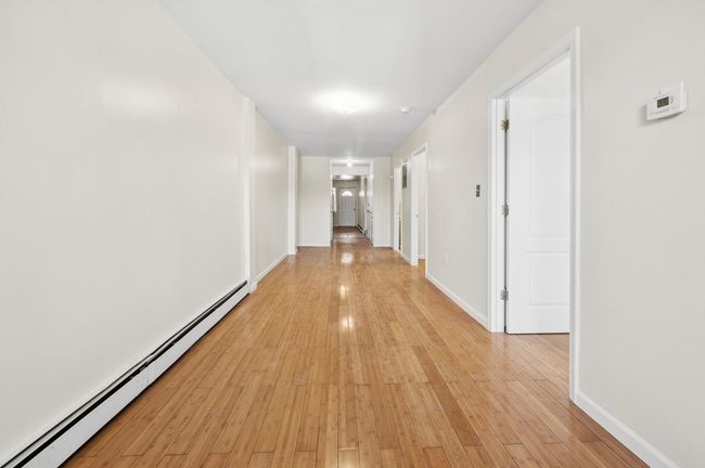 Hallway featuring light wood-type flooring, baseboards, and a baseboard radiator | Image 5