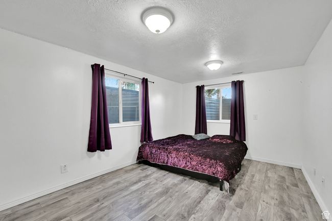 Bedroom featuring a textured ceiling, multiple windows, and wood finished floors | Image 34