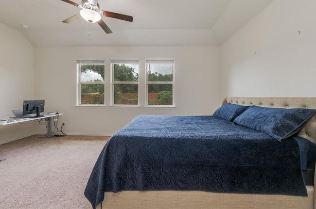 Carpeted bedroom with vaulted ceiling, baseboards, a ceiling fan, and an office area | Image 23