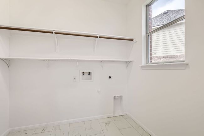 Laundry area featuring electric dryer hookup, light marble finish floors, washer hookup, and baseboards | Image 23