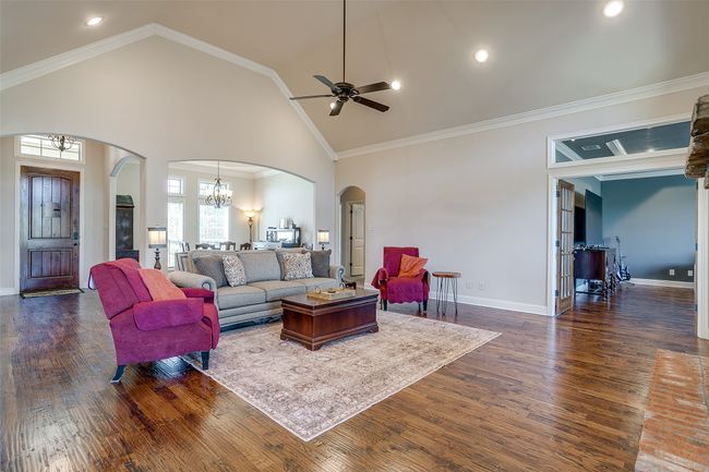 Living area featuring ornamental molding, ceiling fan with notable chandelier, arched walkways, and dark wood-style floors | Image 9