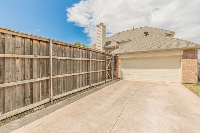 View of patio / terrace featuring fence, an attached garage, and concrete driveway | Image 39