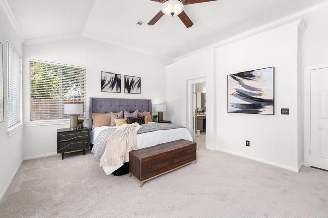 Bedroom with light carpet, crown molding, vaulted ceiling, ceiling fan, and connected bathroom | Image 15