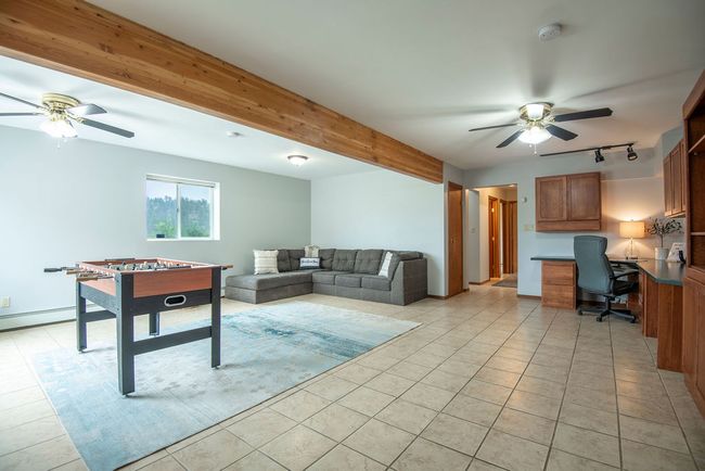 Living room featuring a ceiling fan, track lighting, light tile patterned floors, and built in desk | Image 17