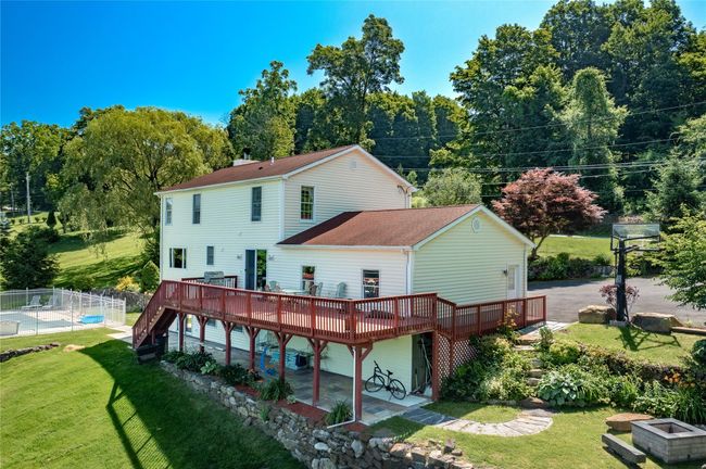 Back of property featuring a wooden deck, roof with shingles, stairway, and a patio | Image 5