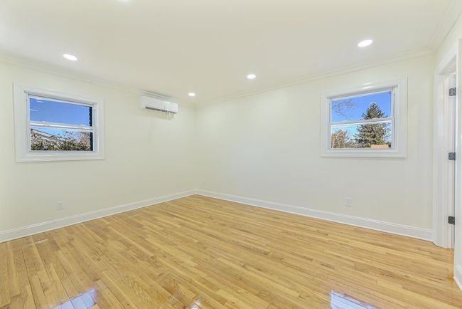 Unfurnished room featuring crown molding, a wealth of natural light, a wall mounted AC, and light hardwood / wood-style flooring | Image 27