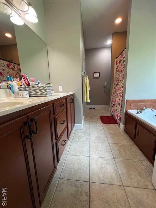 Full bathroom with double vanity, tile patterned flooring, a tub, and a shower with curtain | Image 12