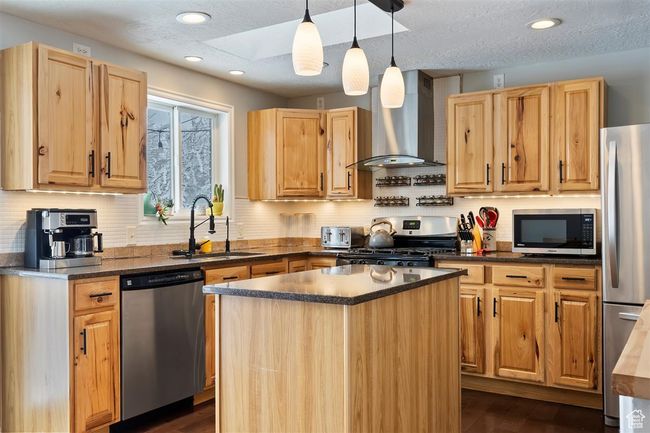 Kitchen featuring stainless steel appliances, wall chimney range hood, a sink, dark wood finished floors, and recessed lighting | Image 17