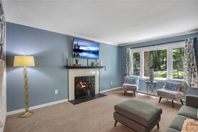 Carpeted living room, large windows, molding and a tiled fireplace | Image 9