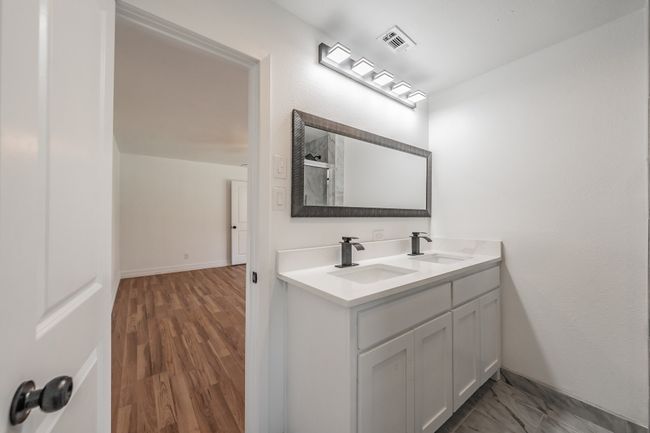 Full bathroom with double vanity, a shower, wood finished floors, and baseboards | Image 20