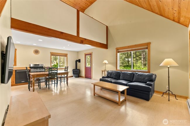 Open-concept main floor integrates kitchen, dining, and living spaces. Vaulted ceilings with exposed beams add warmth and architectural interest. | Image 15