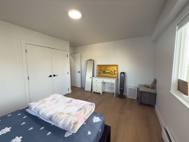 Bedroom with a closet, wood finished floors, baseboards, and baseboard heating | Image 12