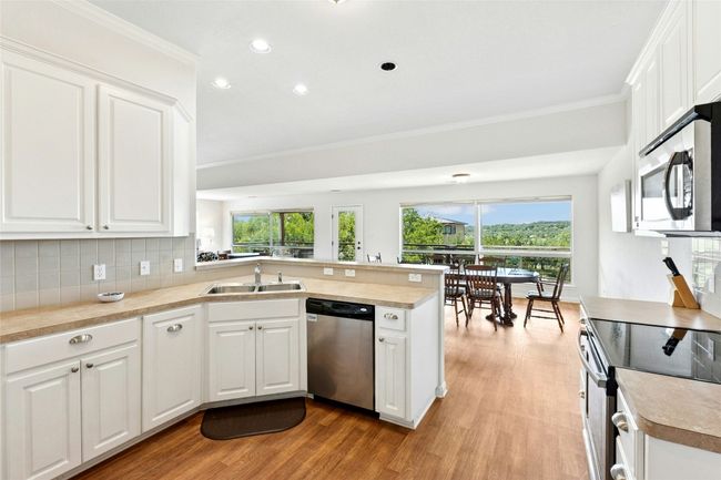 Kitchen featuring stainless steel appliances, a peninsula, plenty of natural light, light wood-style flooring, and ornamental molding | Image 9