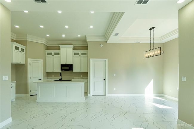 Kitchen featuring an island with sink, marble finish floor, baseboards, and black microwave | Image 29
