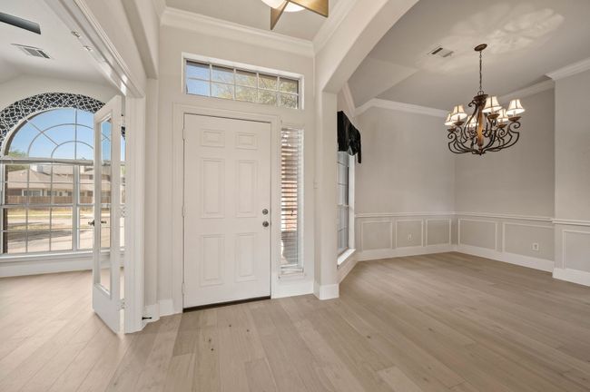 Entrance foyer with wood finished floors, crown molding, a chandelier, and a wealth of natural light | Image 4