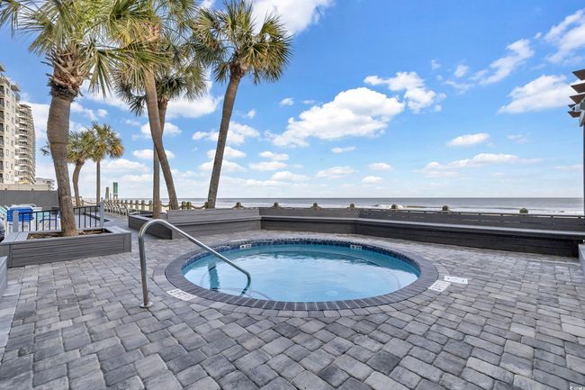 View of swimming pool featuring a hot tub, a water view, and a patio area | Image 26