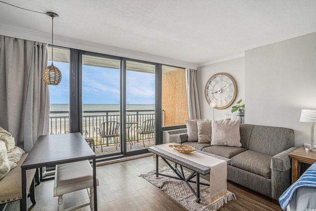 Living room featuring wood finished floors, a water view, crown molding, and an AC wall unit | Image 6