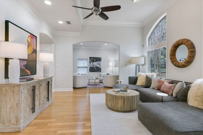 Living room featuring expansive windows looking into the backyard, crown molding, and an arched walkway to the secondary living area. | Image 7