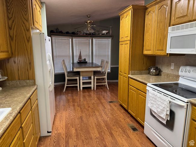 Kitchen featuring white appliances, a ceiling fan, wood finished floors, and light countertops | Image 8
