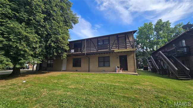 Back of house featuring brick siding, a lawn, stairway, and a wooden deck | Image 4