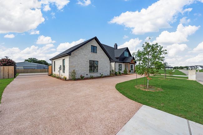 View of front facade with curved driveway, stone siding, a gate, and a chimney | Image 4