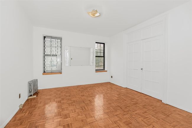 Unfurnished room featuring radiator heating unit and baseboards | Image 7