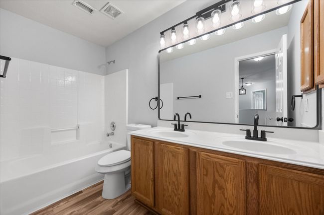 Full bathroom featuring new laminate flooring, double vanity, and shower / bathtub combination | Image 31