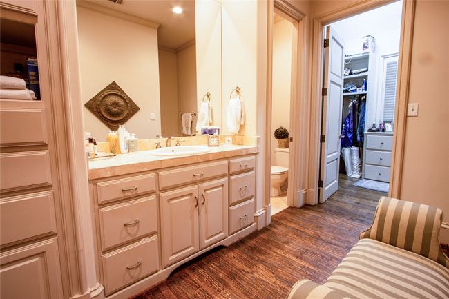 Bathroom featuring crown molding, toilet, vanity, wood finished floors, and a walk in closet | Image 14