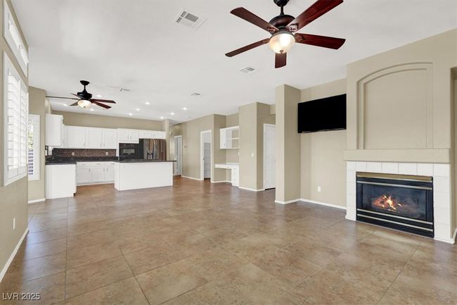 Unfurnished living room featuring ceiling fan and a tile fireplace | Image 11