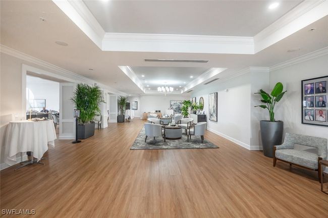 Lobby and sitting area in the main clubhouse with light finished wood floors, a notable chandelier, ornamental molding, and a raised ceiling | Image 31