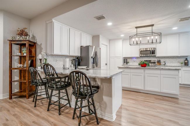 Kitchen featuring stainless steel appliances, a peninsula, decorative backsplash, light wood-style floors, and recessed lighting | Image 11