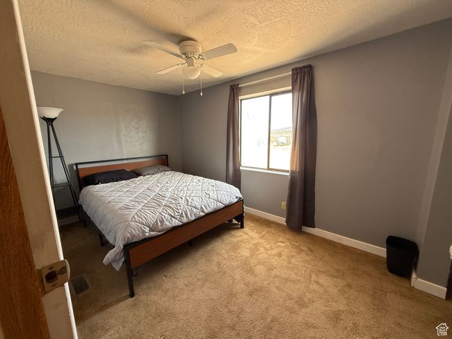 Carpeted bedroom with a textured ceiling, a ceiling fan, and baseboards | Image 6