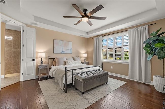 Bedroom with a raised ceiling, ceiling fan, and dark wood-type flooring | Image 16
