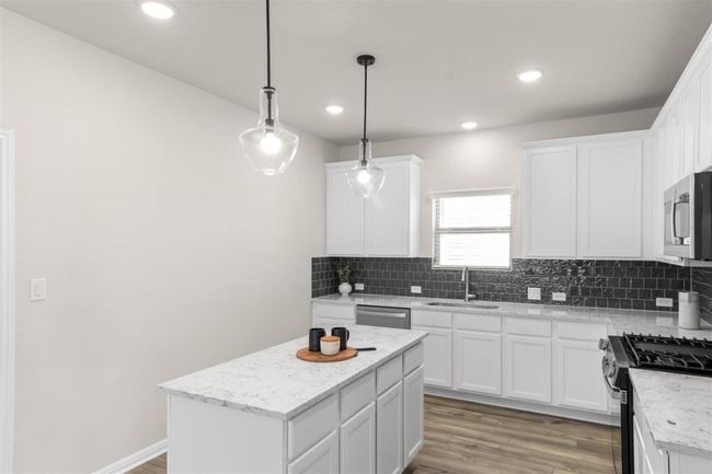 Kitchen featuring light wood finished floors, a sink, backsplash, and appliances with stainless steel finishes | Image 17