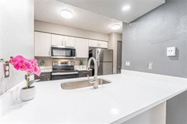 Kitchen with appliances with stainless steel finishes, light countertops, white cabinetry, and a peninsula | Image 12