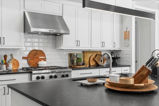 The kitchen offers an oversized island with leathered granite and unique pendant piece. | Image 16